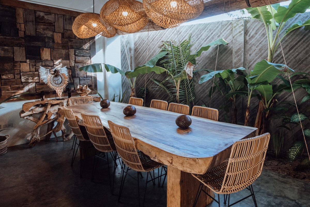 Villa Tulua dining area with hand-carved wooden table and rattan pendant lights