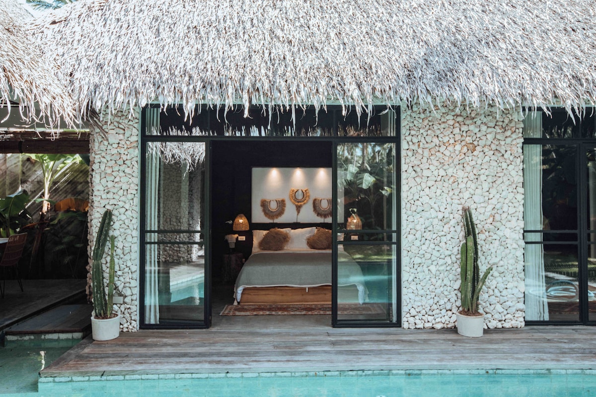 Bedroom view through glass doors with elegant bed and tribal art decor